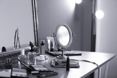 Photo of Different makeup products on dressing table, black and white effect
