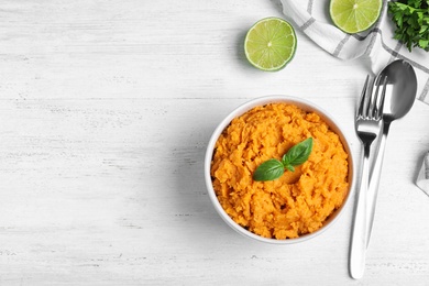 Flat lay composition with mashed sweet potatoes on wooden background, space for text