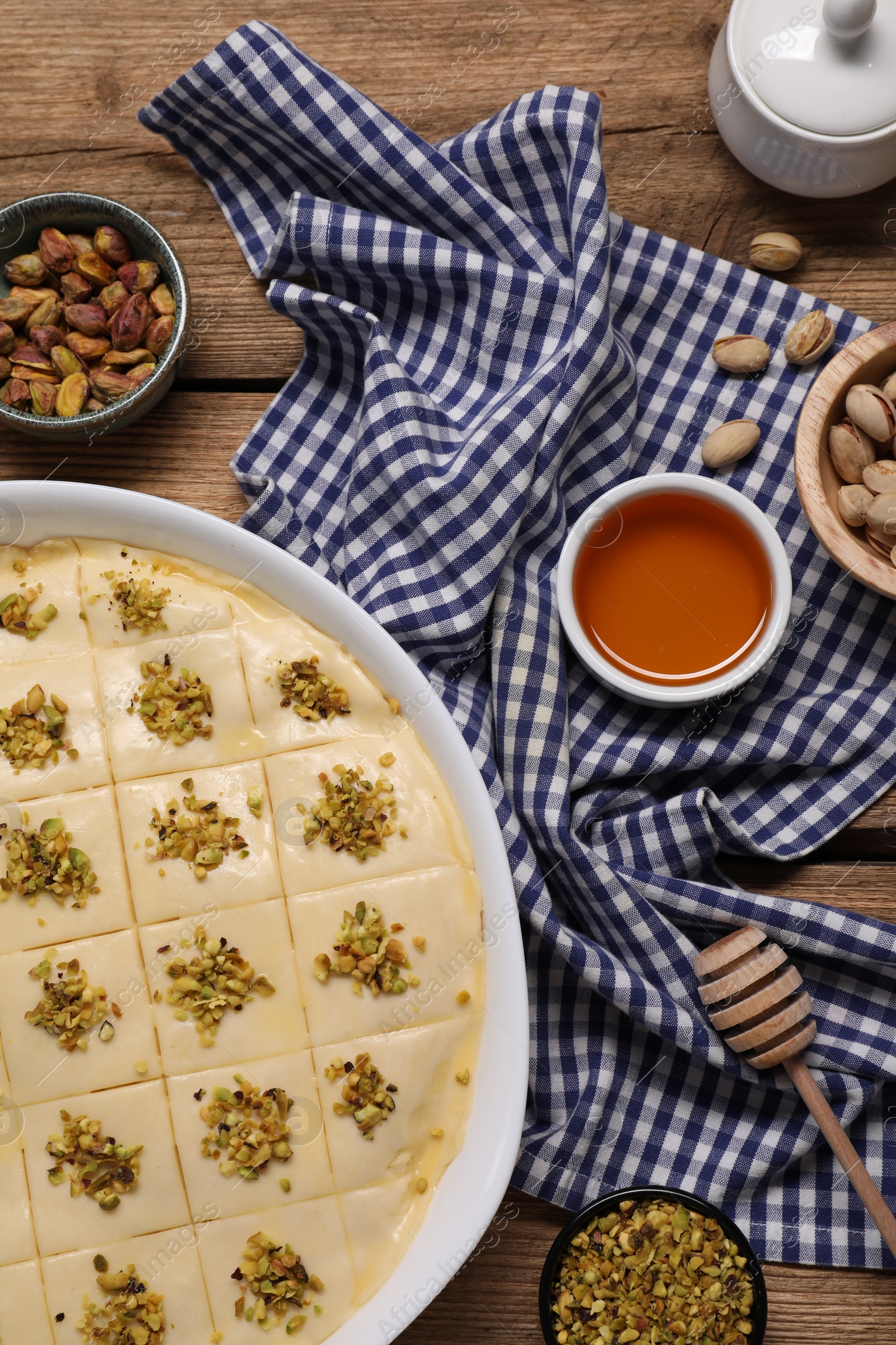 Photo of Making delicious baklava. Raw dough with ingredients on wooden table, flat lay