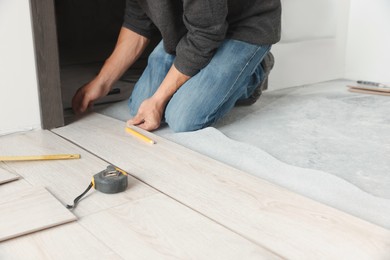 Photo of Worker installing new laminate flooring in room, closeup