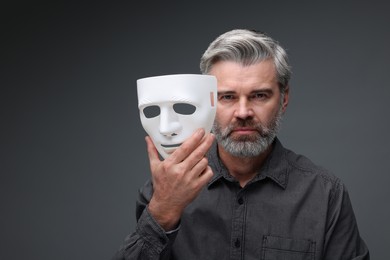 Photo of Multiple personality concept. Man with mask on dark grey background, space for text