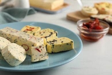 Photo of Different types of tasty butter and chili pepper on white marble table, closeup