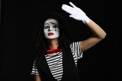 Photo of Young woman in mime costume posing on black background