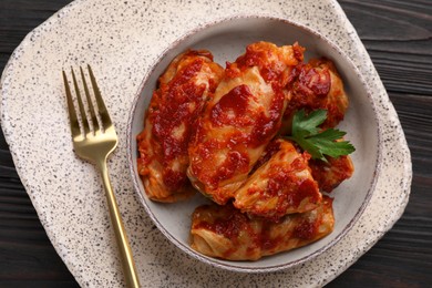 Photo of Delicious stuffed cabbage rolls cooked with homemade tomato sauce on wooden table, top view