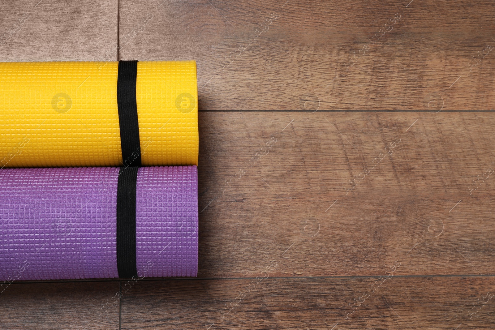 Photo of Bright rolled camping mats on wooden background, flat lay. Space for text