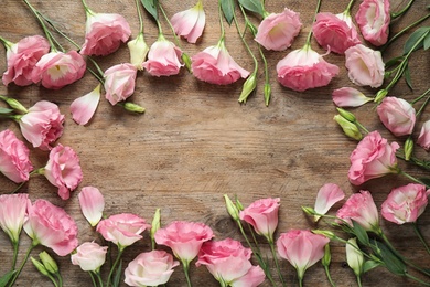 Photo of Flat lay composition with beautiful Eustoma flowers on wooden table, space for text