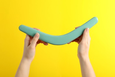 Woman holding boomerang on yellow background, closeup