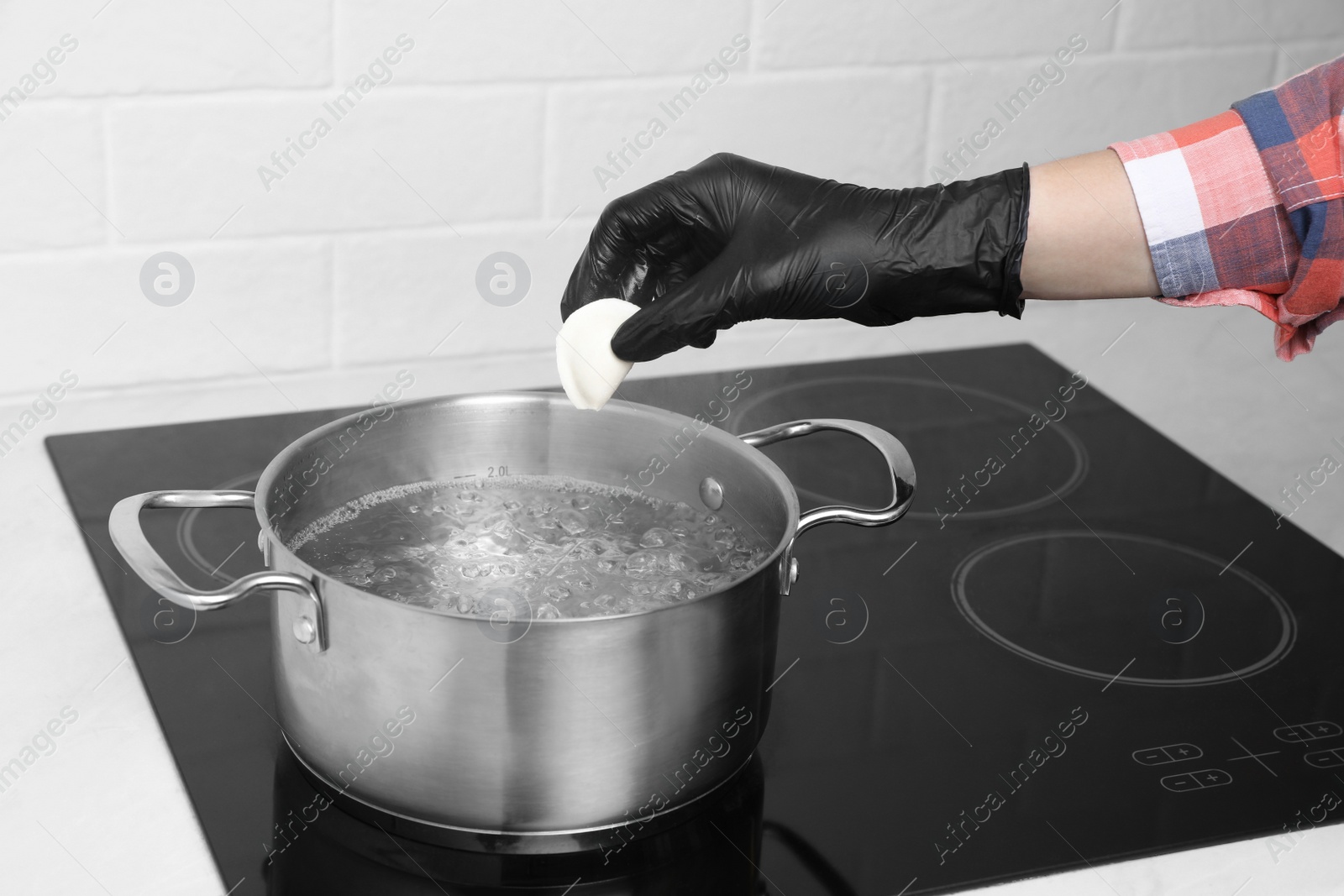 Photo of Woman cooking delicious dumplings in kitchen, closeup