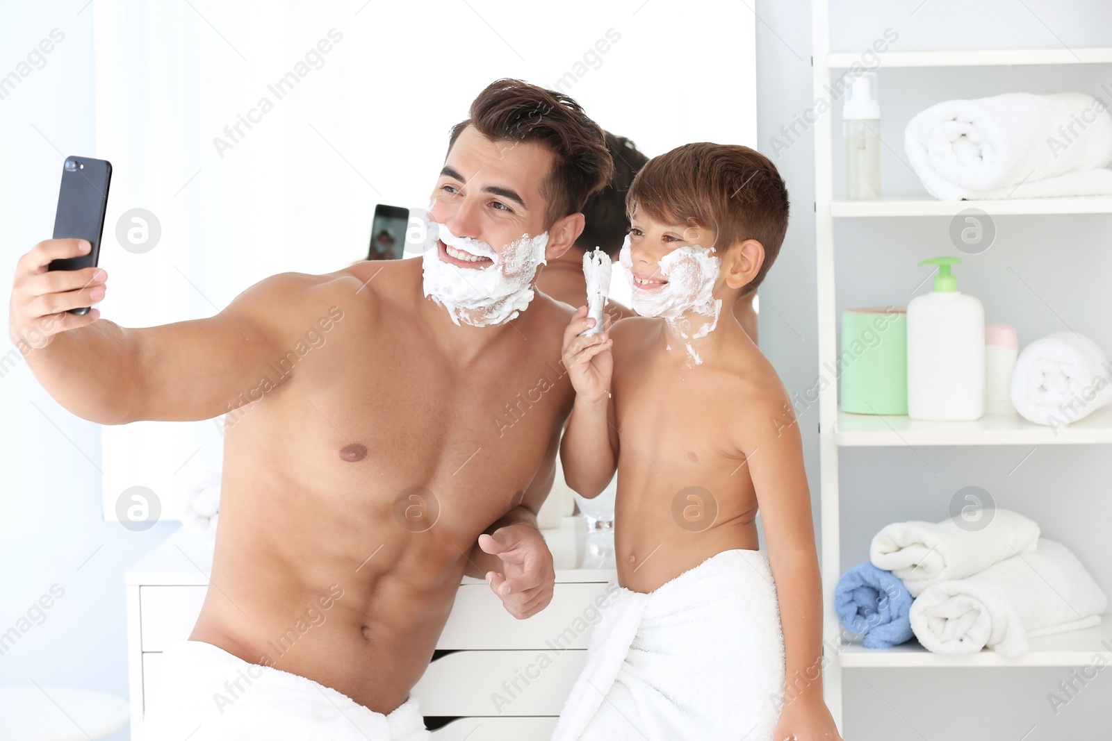 Photo of Father and son taking selfie while shaving in bathroom