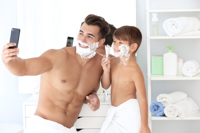 Photo of Father and son taking selfie while shaving in bathroom