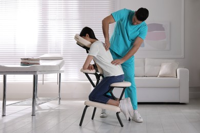 Photo of Woman receiving massage in modern chair indoors