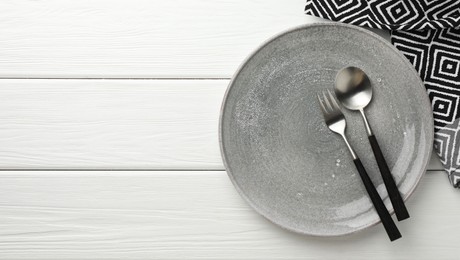 Photo of Stylish setting with cutlery, napkin and plate on white wooden table, top view. Space for text