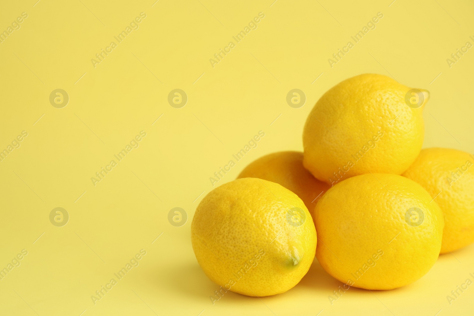 Photo of Fresh ripe lemons on yellow background. Space for text