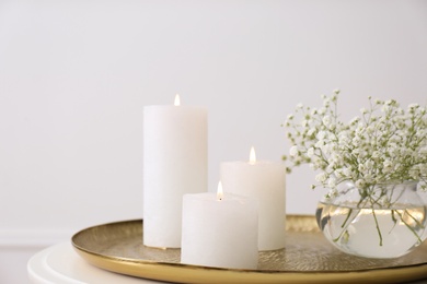 Photo of Vase with beautiful flowers and burning candles on table indoors, closeup. Interior elements