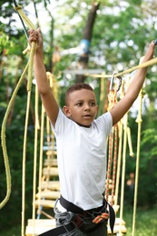 Little African-American boy climbing in adventure park. Summer camp