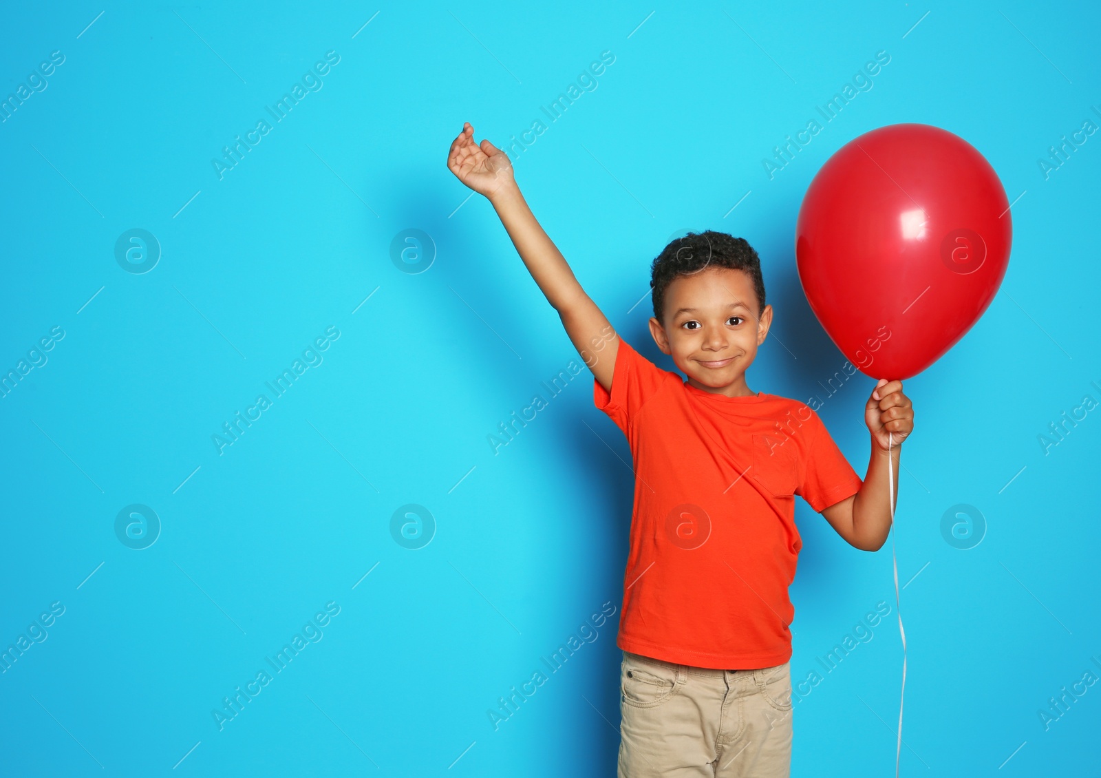 Photo of Cute African-American boy with balloon on color background. Birthday celebration