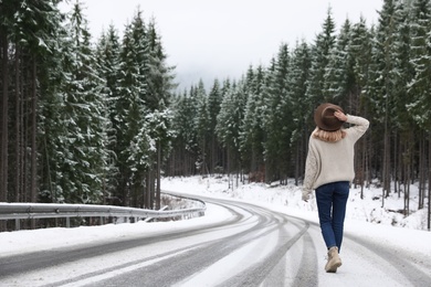 Photo of Young woman walking near snowy forest. Winter vacation