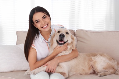 Photo of Young woman and her Golden Retriever dog on couch in living room