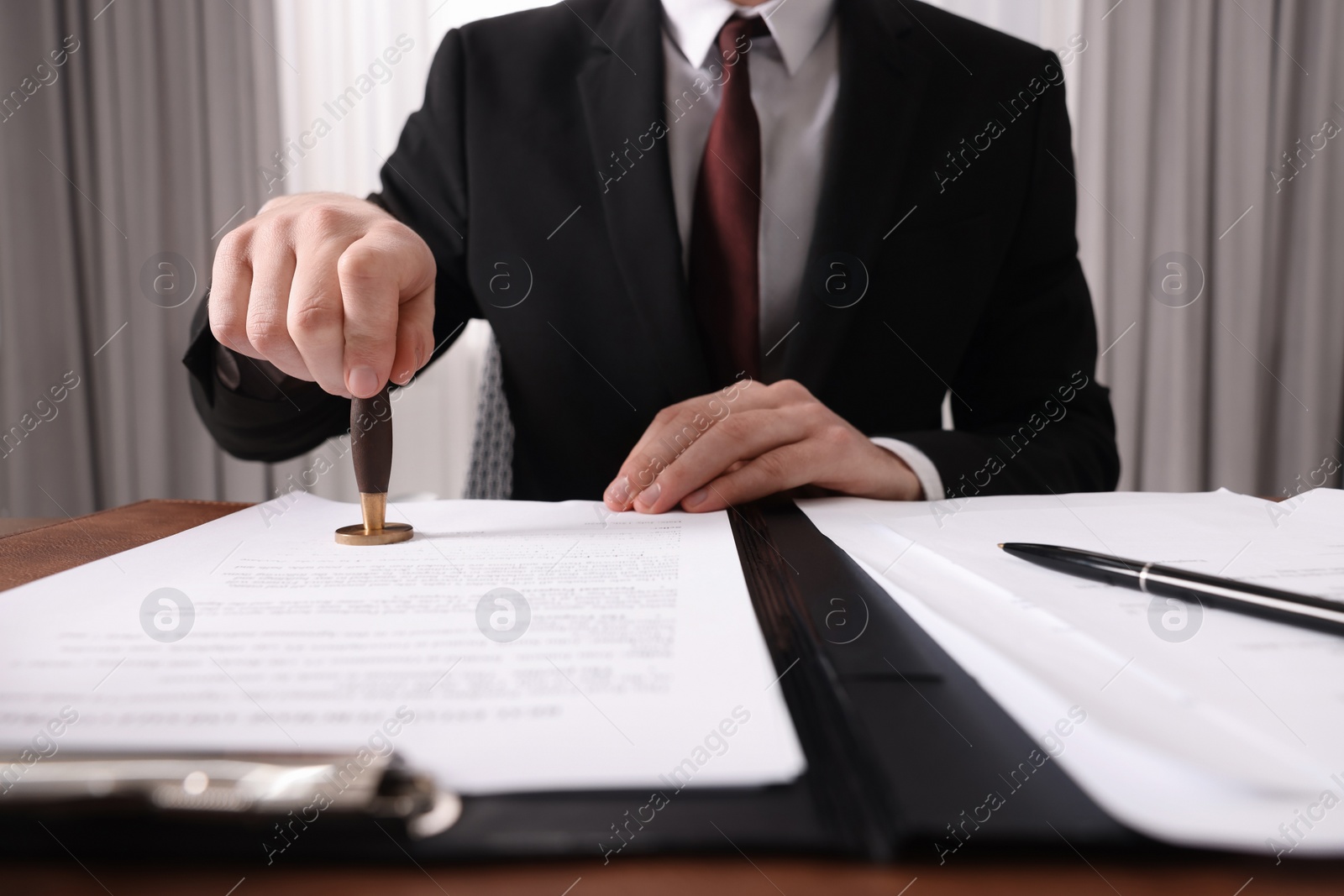 Photo of Notary stamping document at table in office, closeup