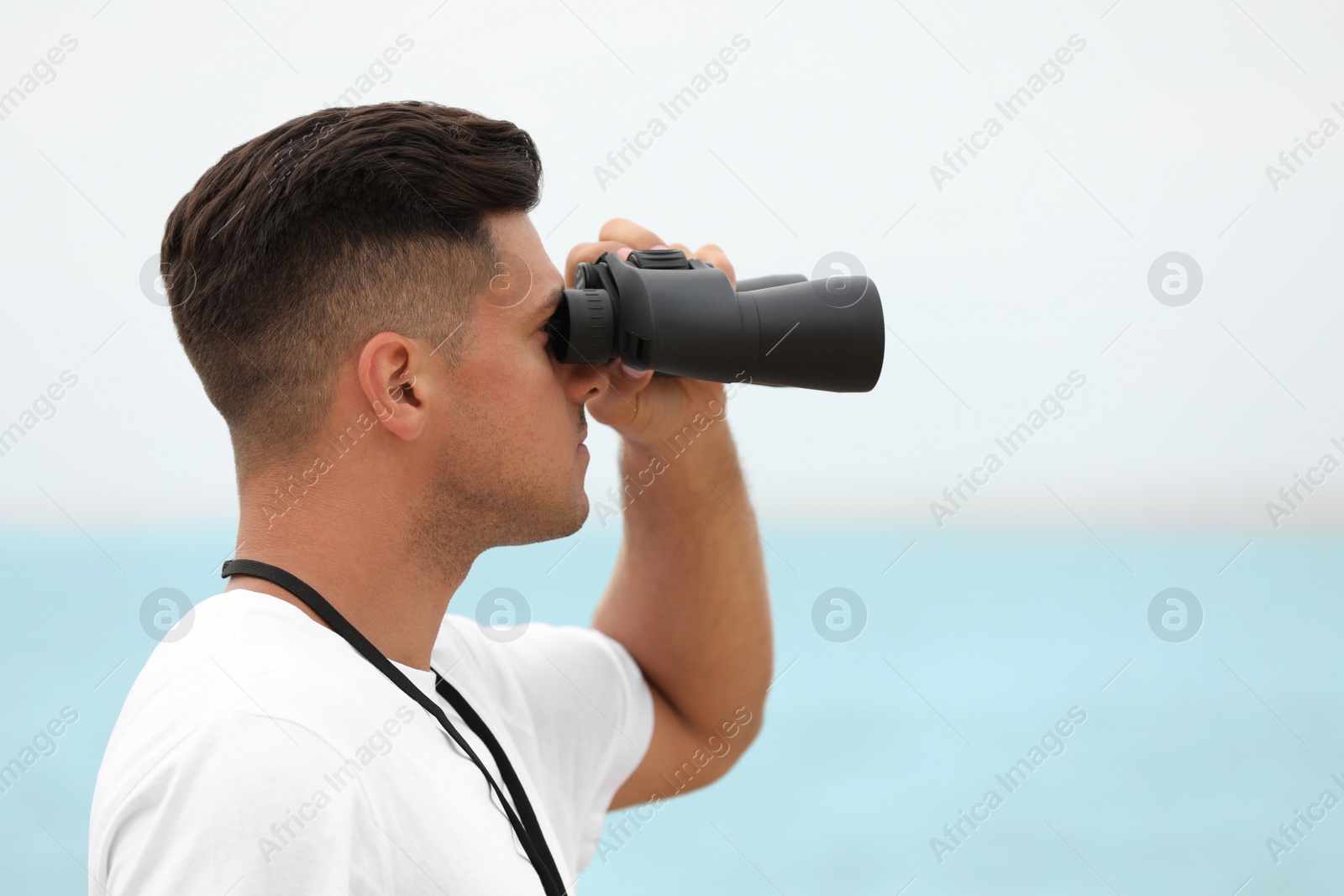 Photo of Handsome male lifeguard with binocular near sea