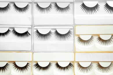 Photo of Set with different false eyelashes in packs as background, top view