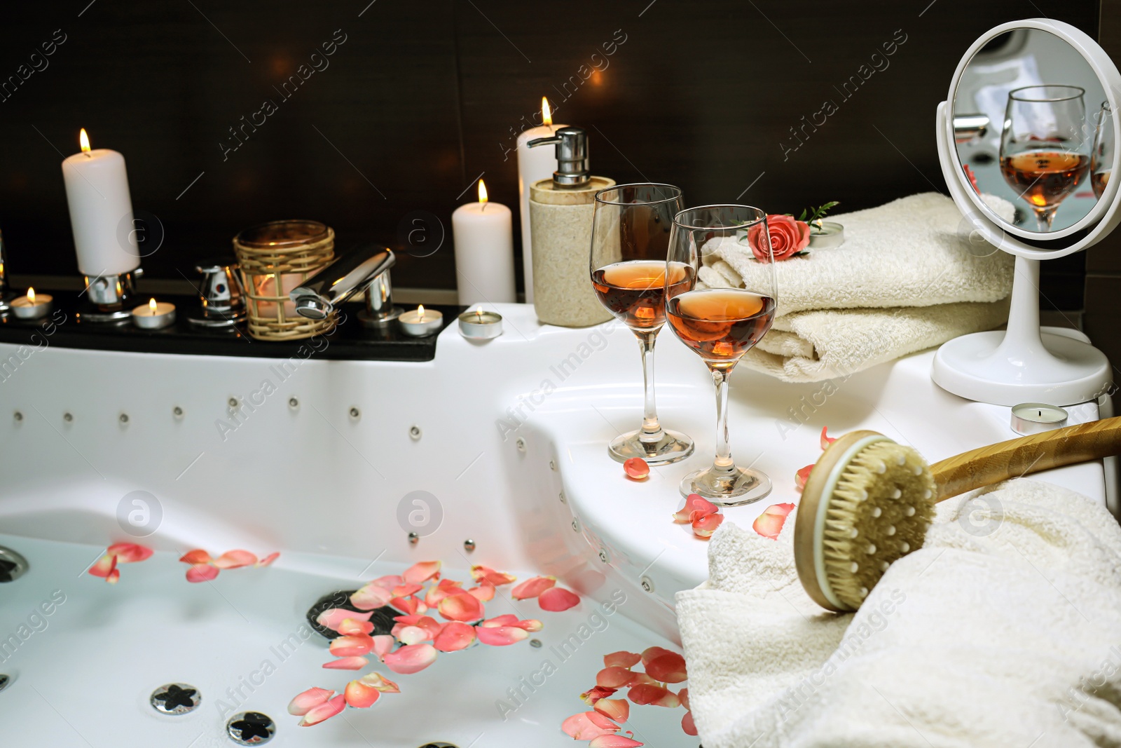 Photo of Bathtub with glasses of wine and candles indoors. Romantic atmosphere