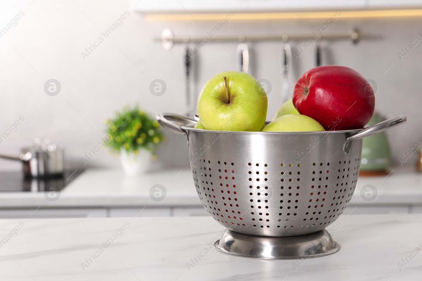 Photo of Colander with fresh apples on white marble table in kitchen. Space for text