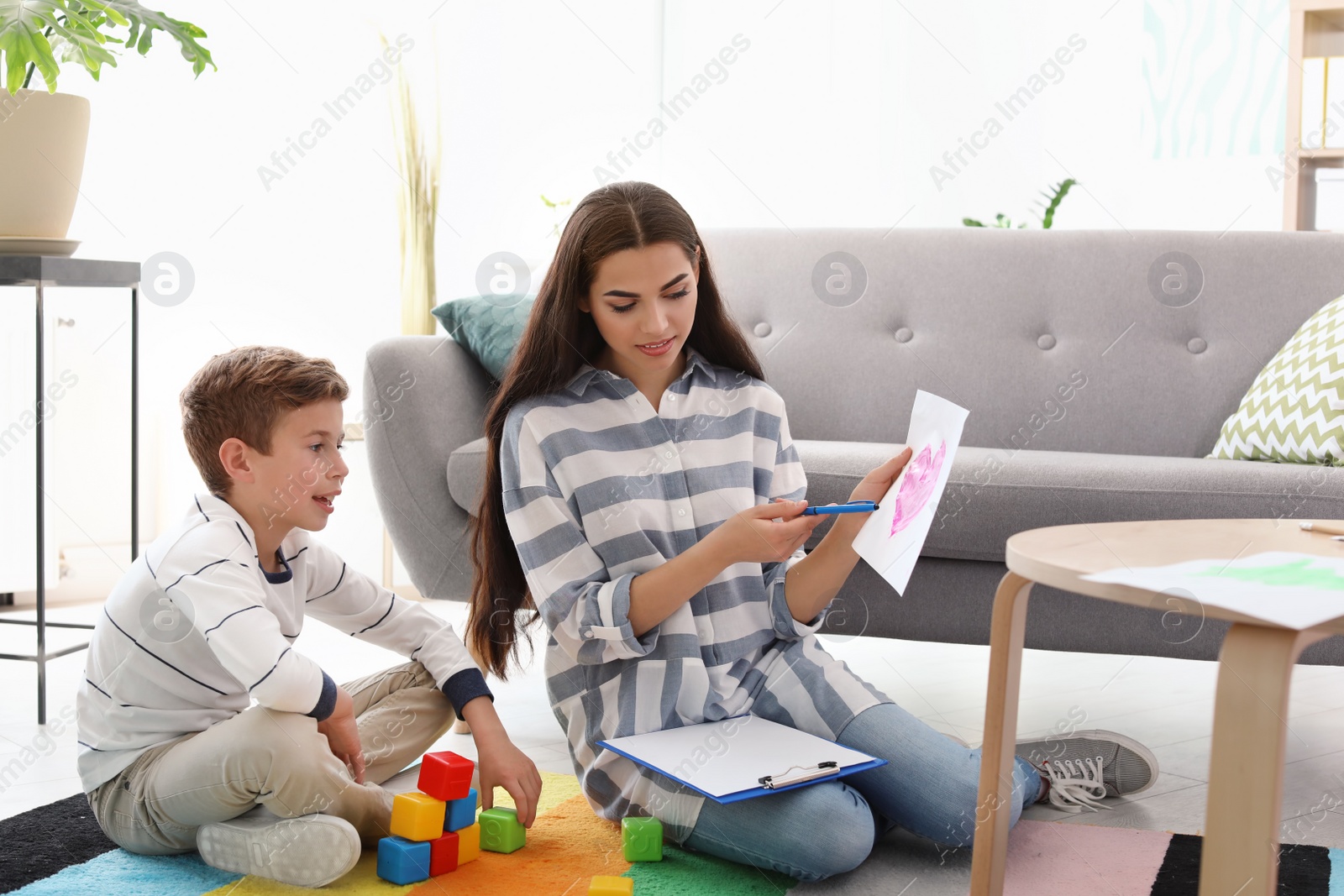 Photo of Child psychologist working with little boy in office. Art therapy