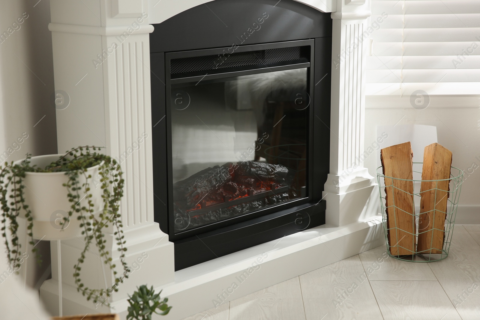 Photo of Bright living room interior with artificial fireplace and firewood in basket