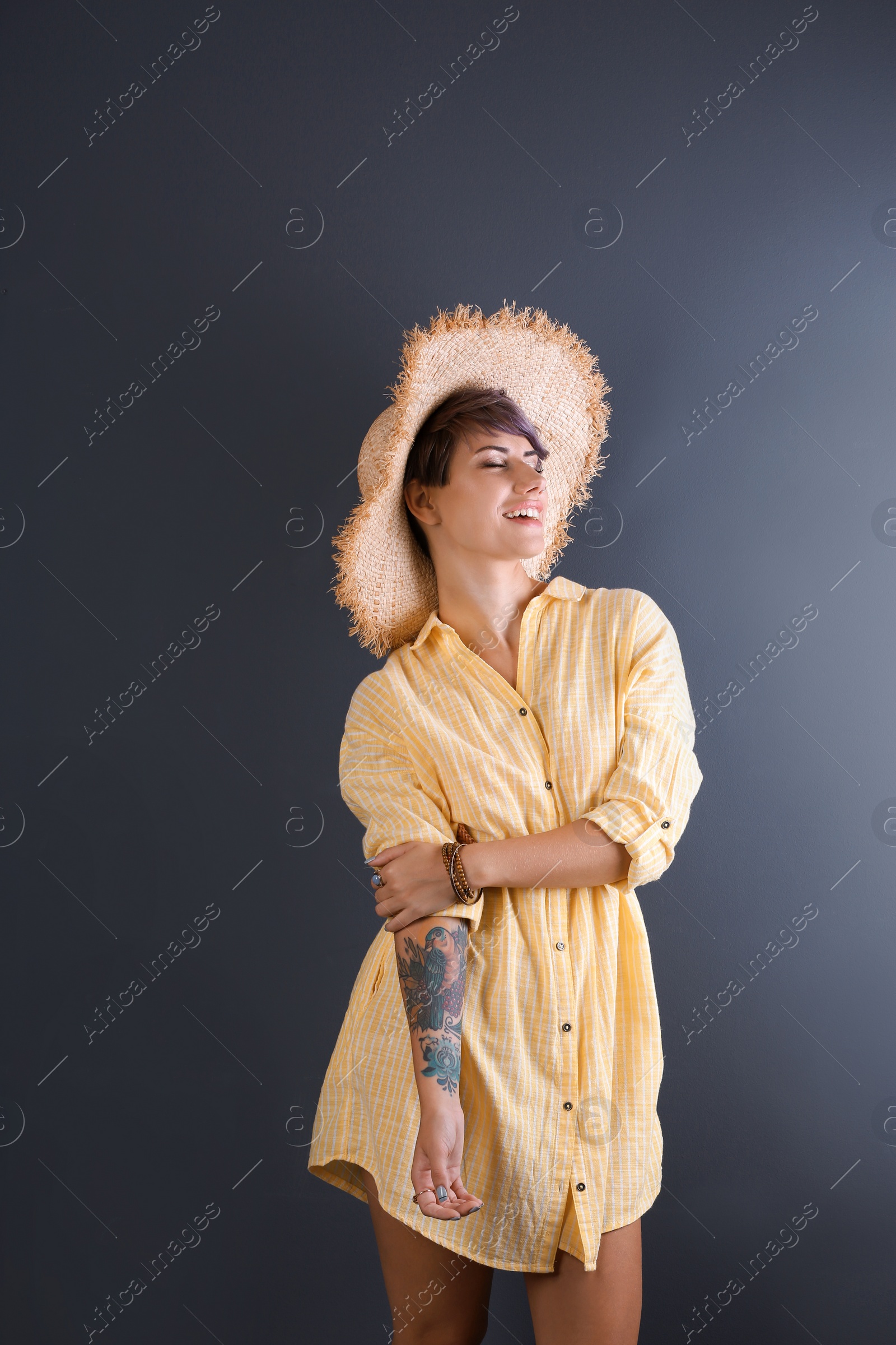 Photo of Trendy young woman with tattoo on color background