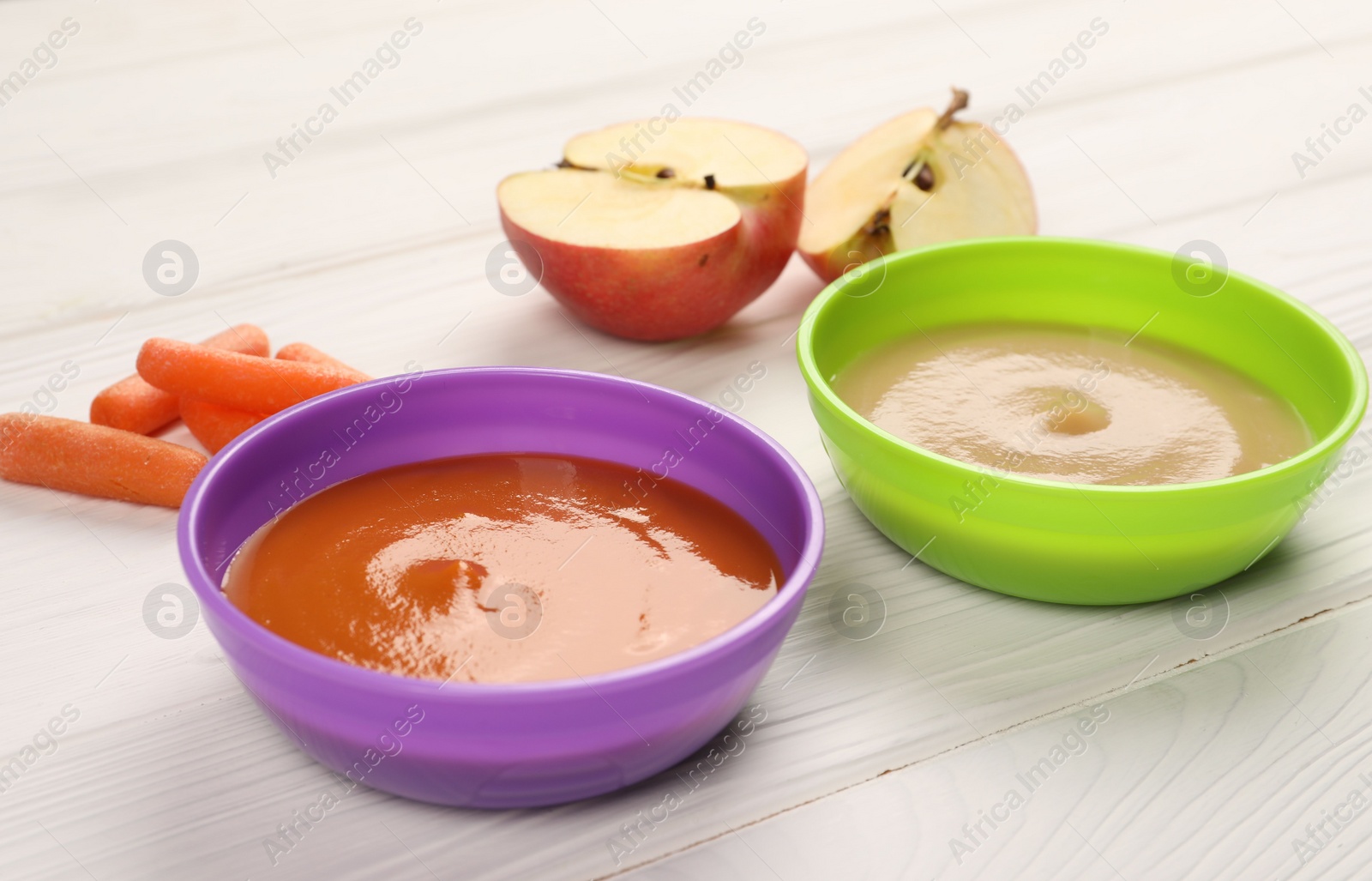 Photo of Baby food. Purees of apples and carrots in bowls on white wooden table