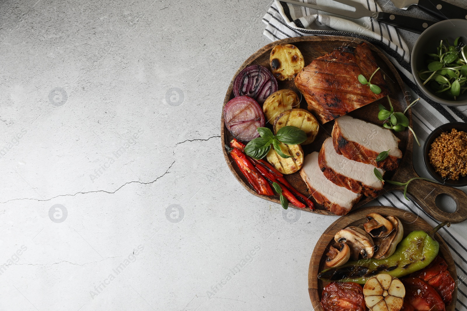 Photo of Delicious grilled meat and vegetables served on light grey table, flat lay. Space for text