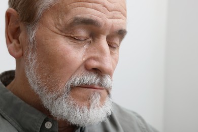 Upset senior man crying indoors, closeup. Loneliness concept