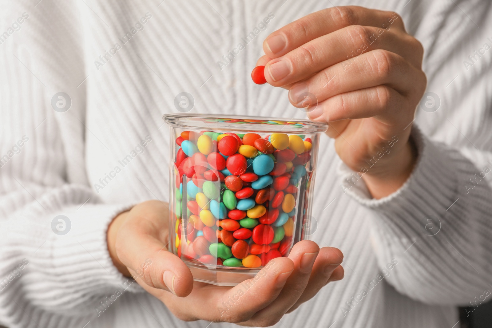 Photo of Woman with glass of tasty colorful candies, closeup