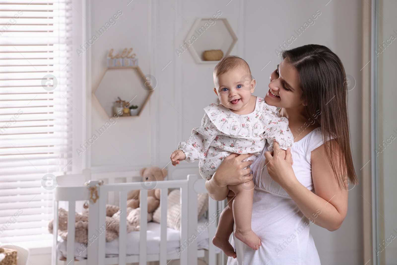 Photo of Happy young mother with her baby daughter in nursery. Space for text