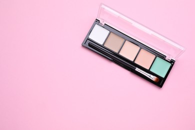 Photo of Colorful contouring palette and brush on pale pink background, top view with space for text. Professional cosmetic product