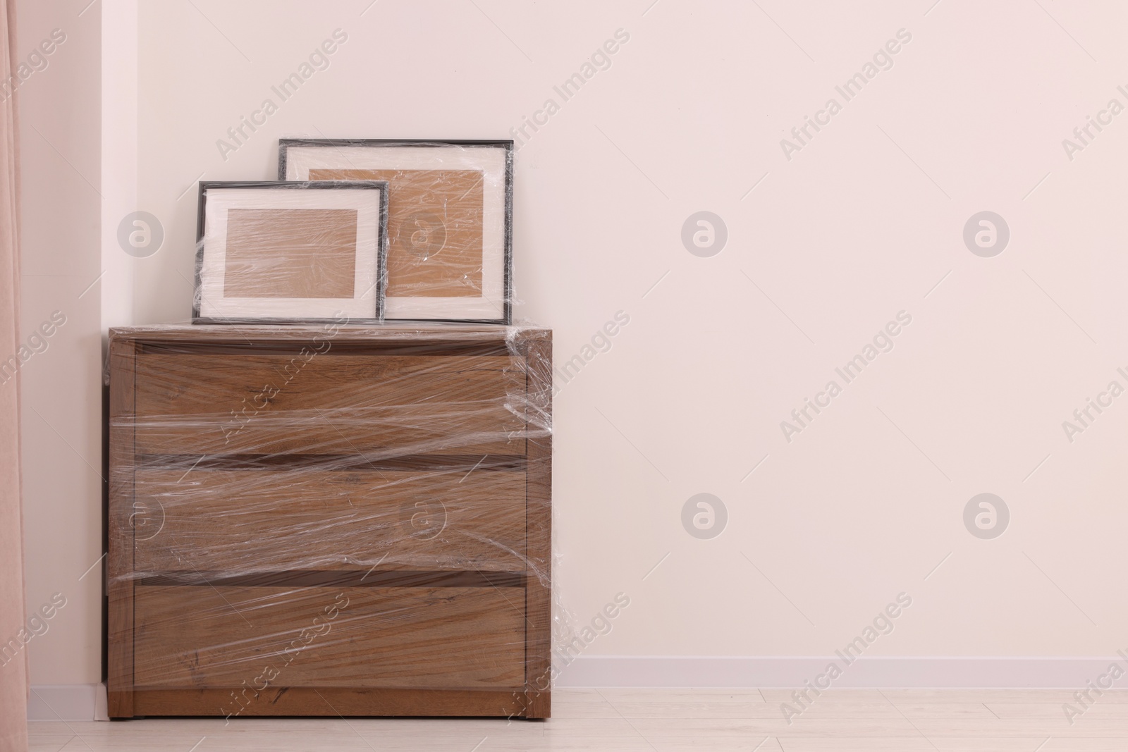 Photo of Picture frames and chest of drawers wrapped in stretch film indoors