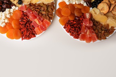 Plates with different dried fruits on white background, top view. Space for text