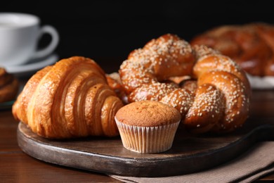 Different tasty freshly baked pastries on wooden table, closeup