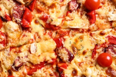 Delicious pizza with sausages and tomatoes, closeup