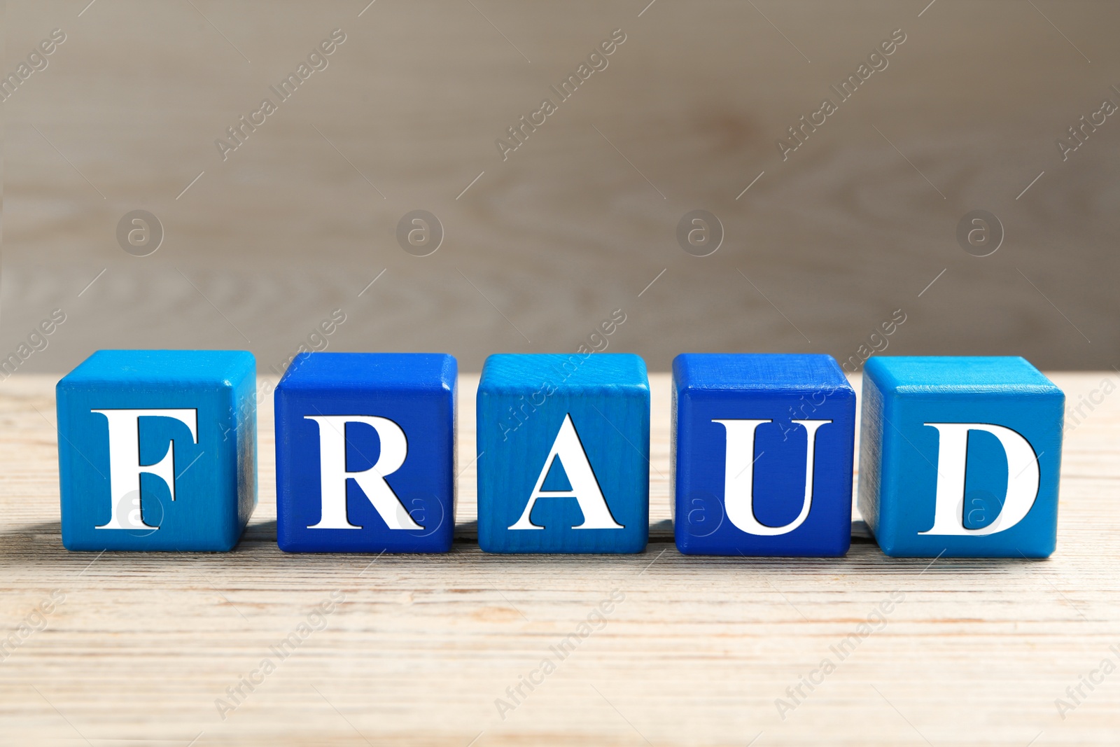 Photo of Word Fraud of cubes with letters on white wooden background