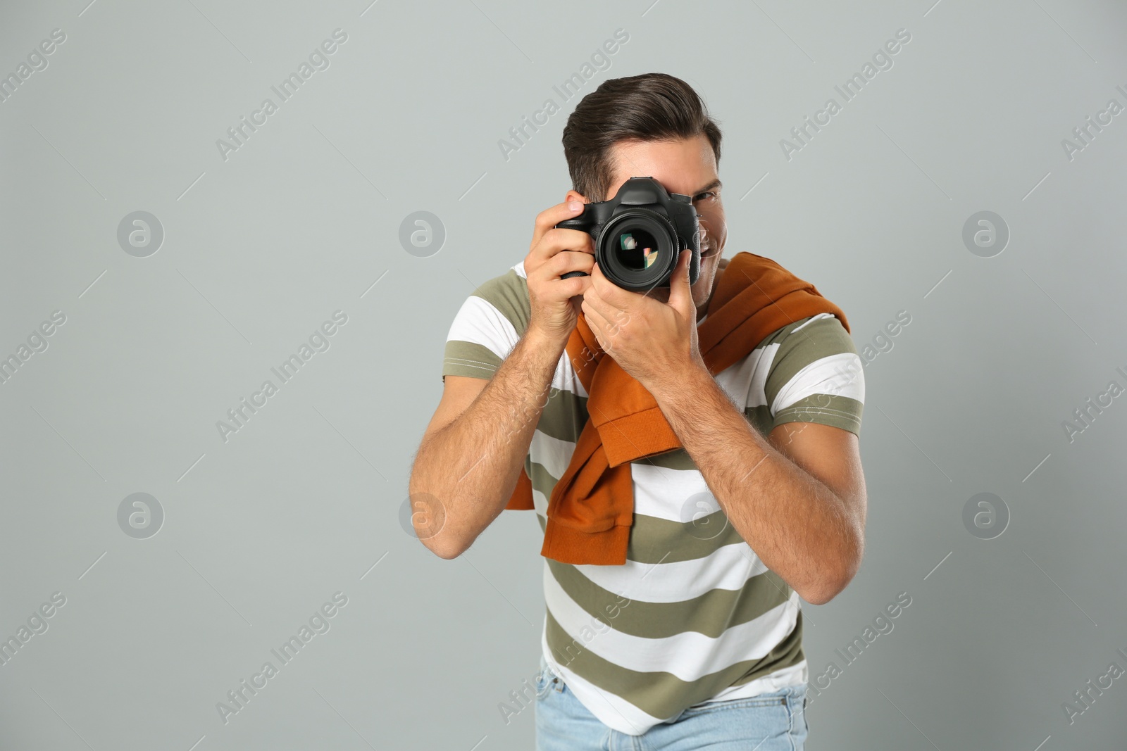 Photo of Professional photographer working on light grey background in studio. Space for text