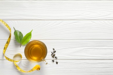 Photo of Flat lay composition with herbal diet tea and measuring tape on white wooden table, space for text. Weight loss concept