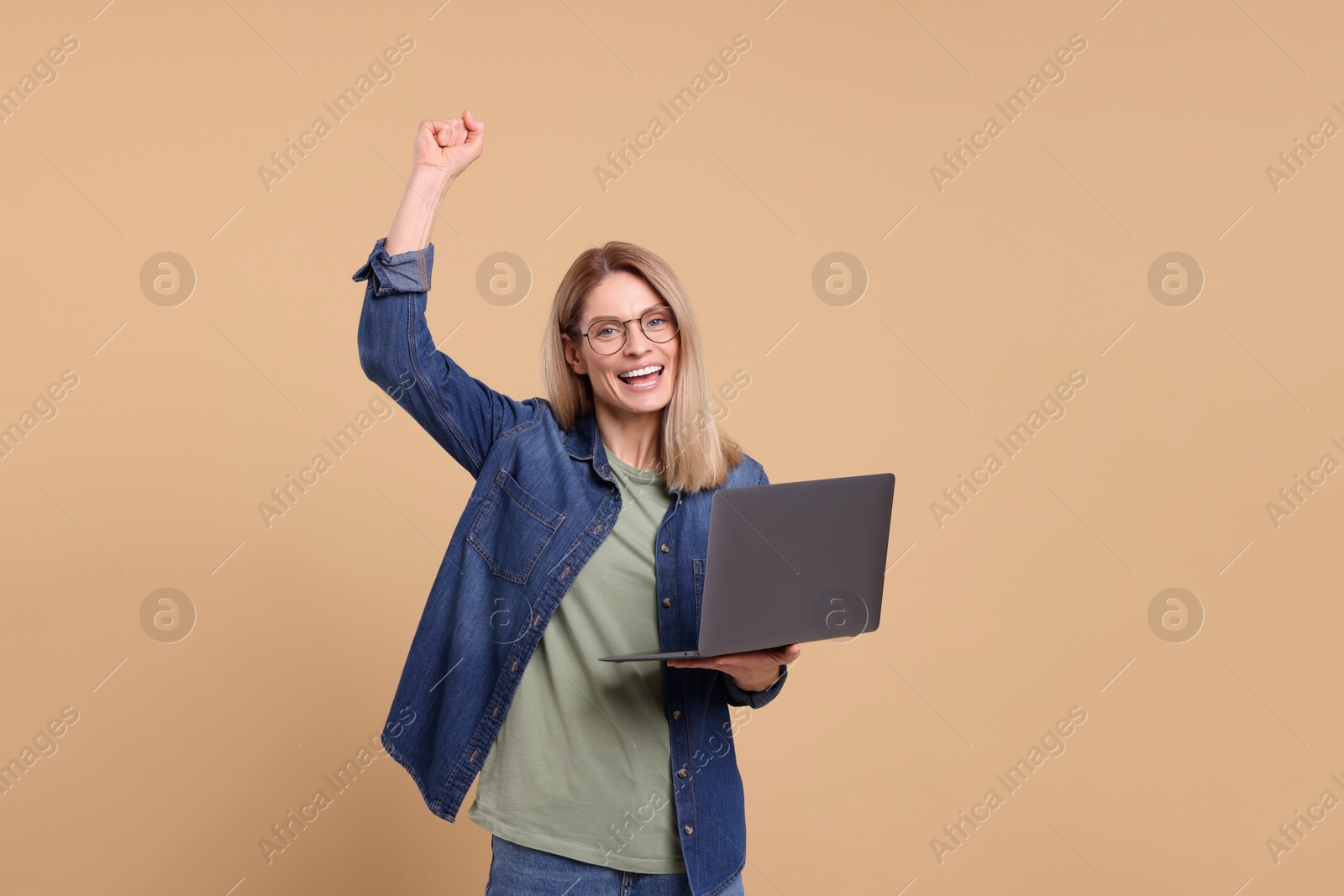 Photo of Emotional woman with laptop on beige background. Space for text