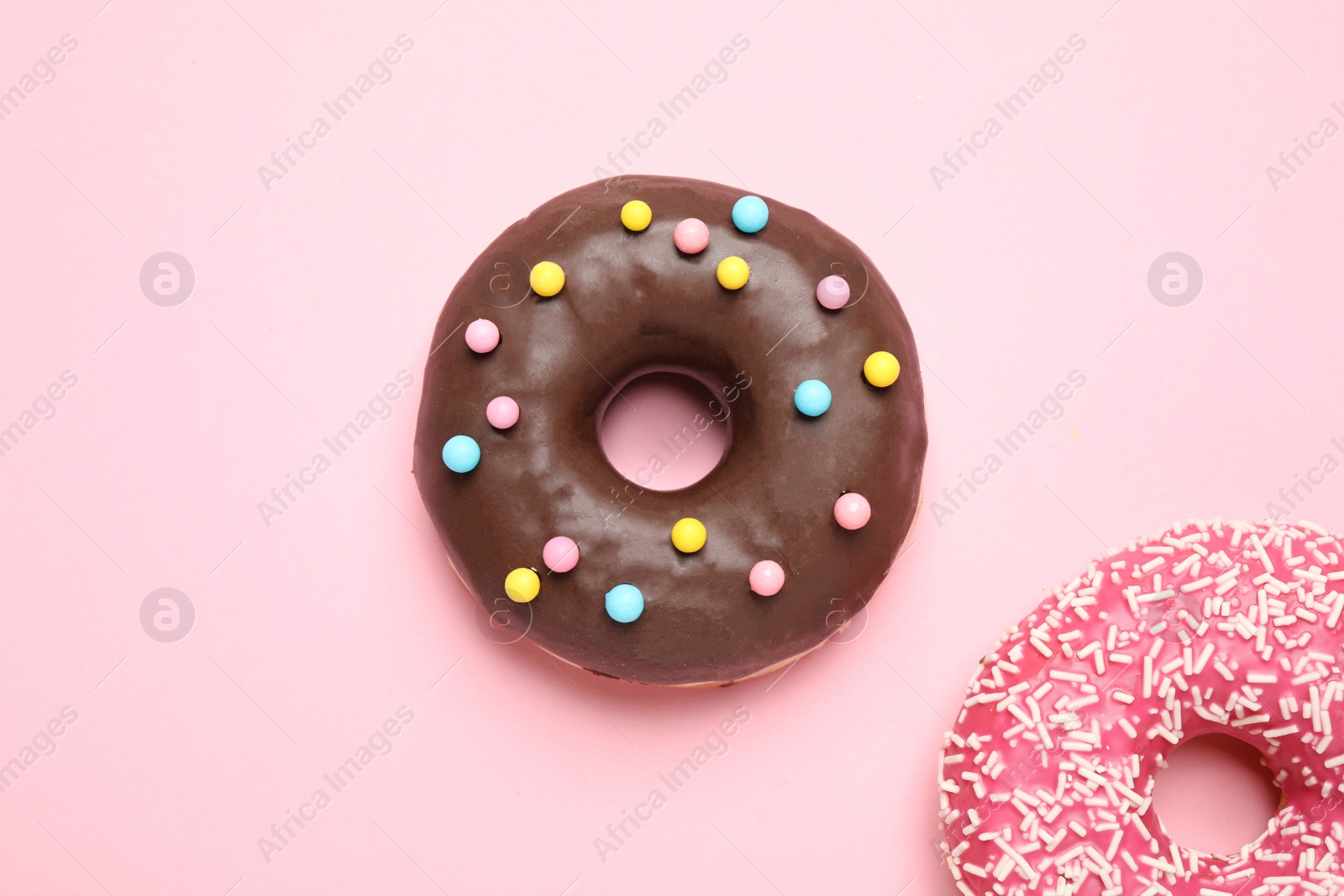 Photo of Delicious glazed donuts on pink background, flat lay