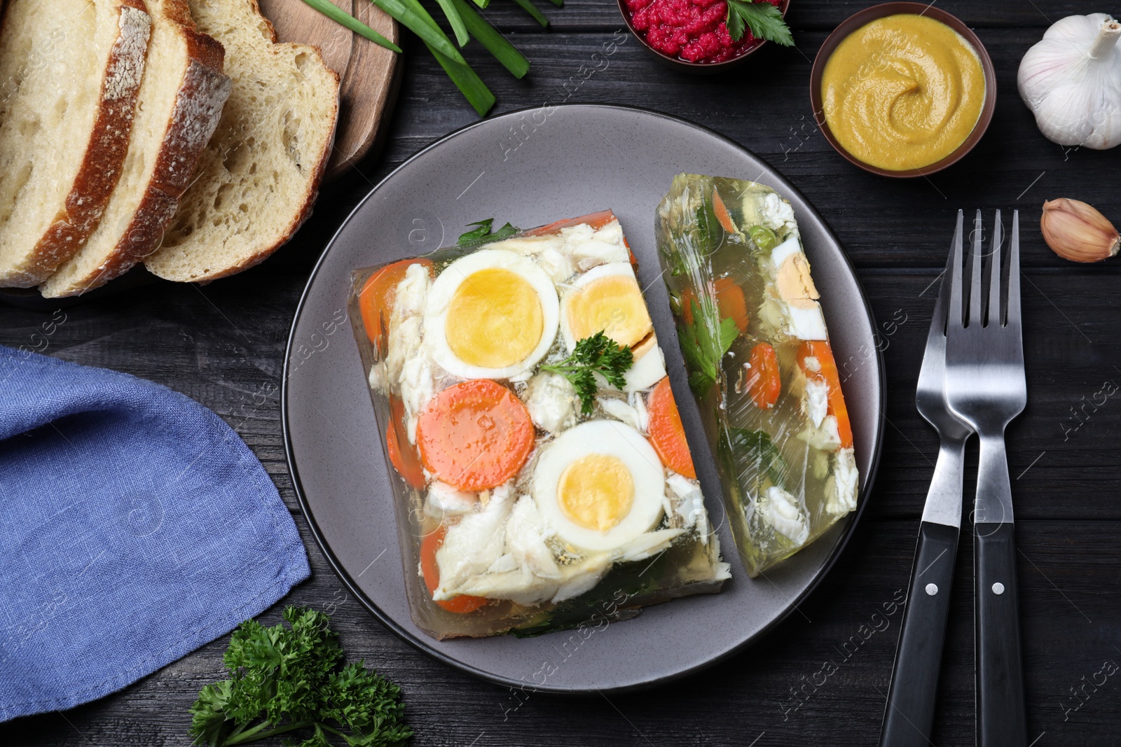 Photo of Delicious fish aspic served on black wooden table, flat lay