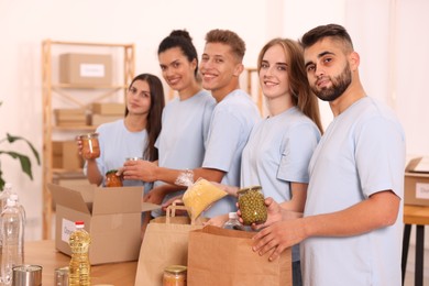 Photo of Portrait of volunteers packing food products at table in warehouse
