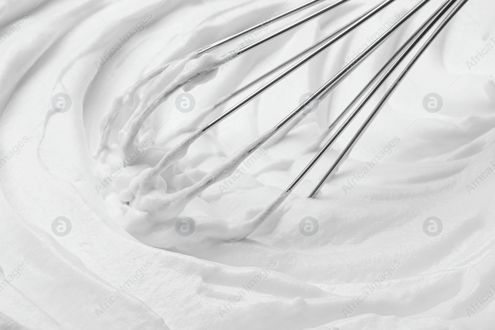 Photo of Whipping white cream with balloon whisk, closeup view