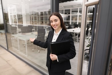 Photo of Female real estate agent with leather portfolio inviting inside