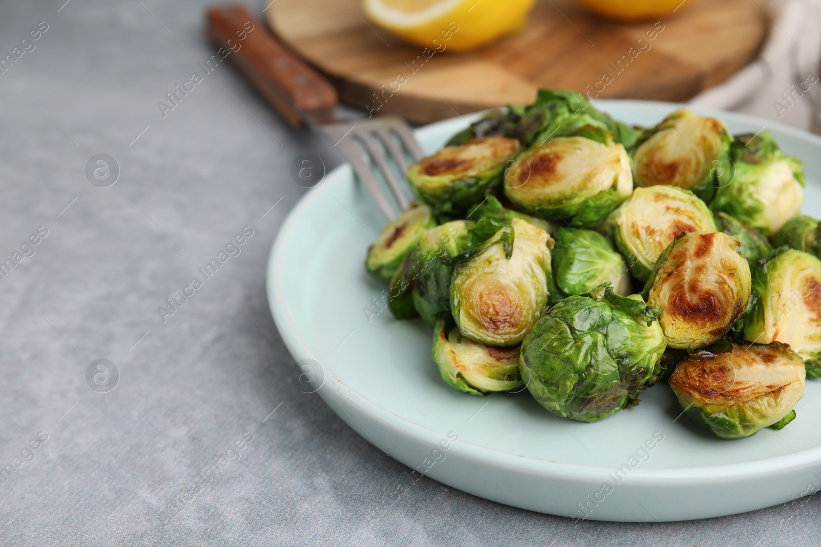 Photo of Delicious roasted Brussels sprouts on grey table, closeup. Space for text